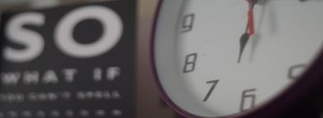 clock with red trim on a wall next to a vision testing panel