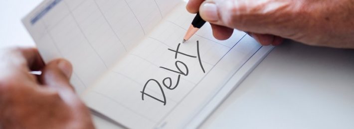 man writing the word "debt" in bank book