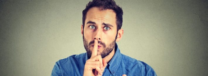 young handsome man giving shhhh quiet, silence, secret gesture isolated on gray wall background